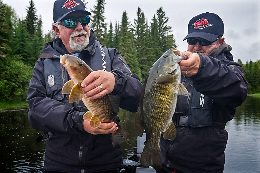 anglers holding a sucker and a smallmouth bass