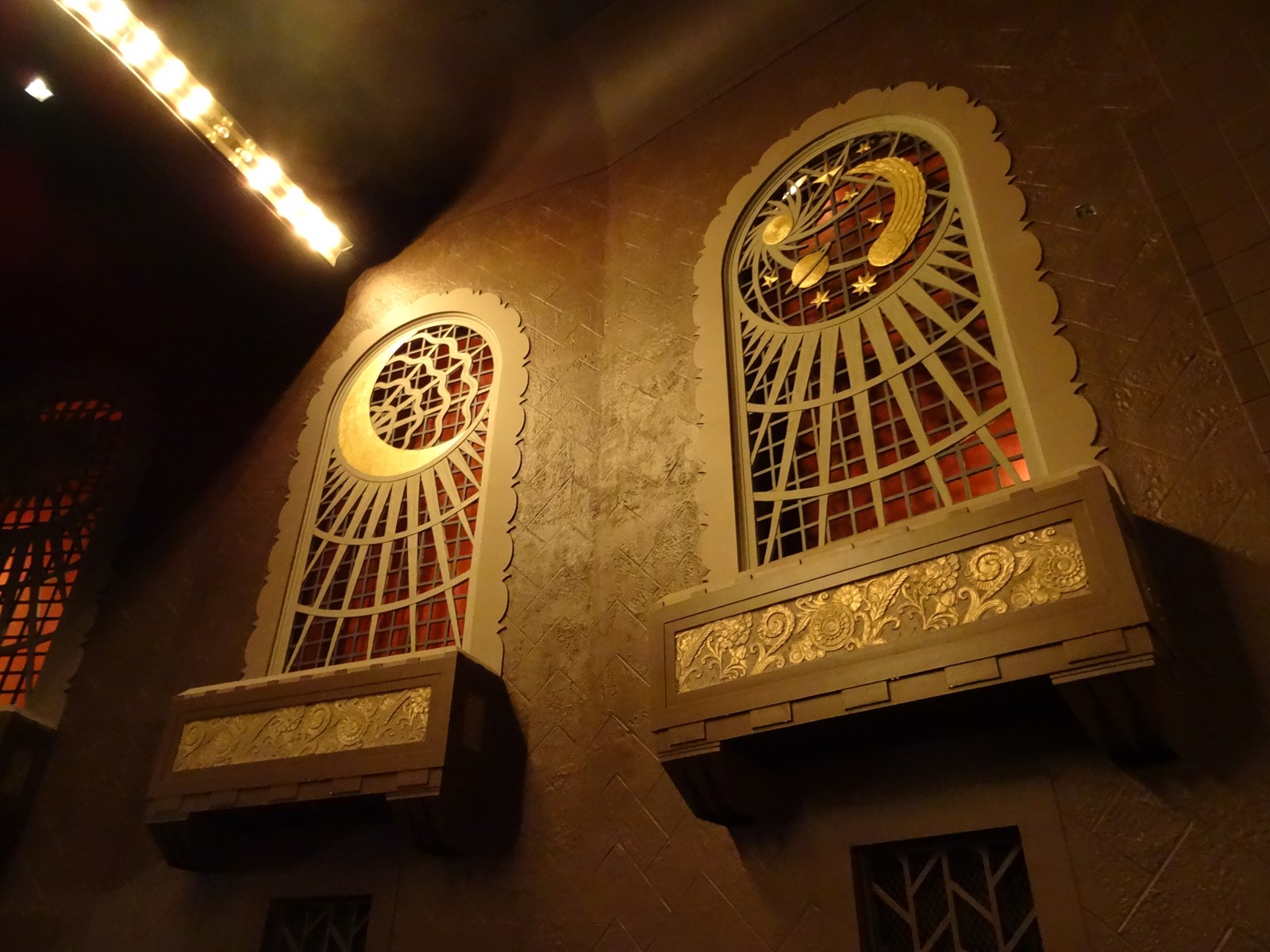 Tall art-deco style stained glass windows in Capitol Centre in North Bay, featuring a sun, moon and planet motif.