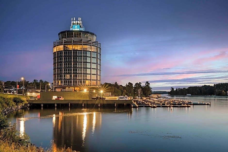 The Clarion Lakeside Inn; a tall, waterside cylindrical tower largely made of glass, lit up at sunset.