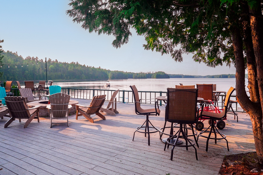 chairs and table on a deck overlooking a lake