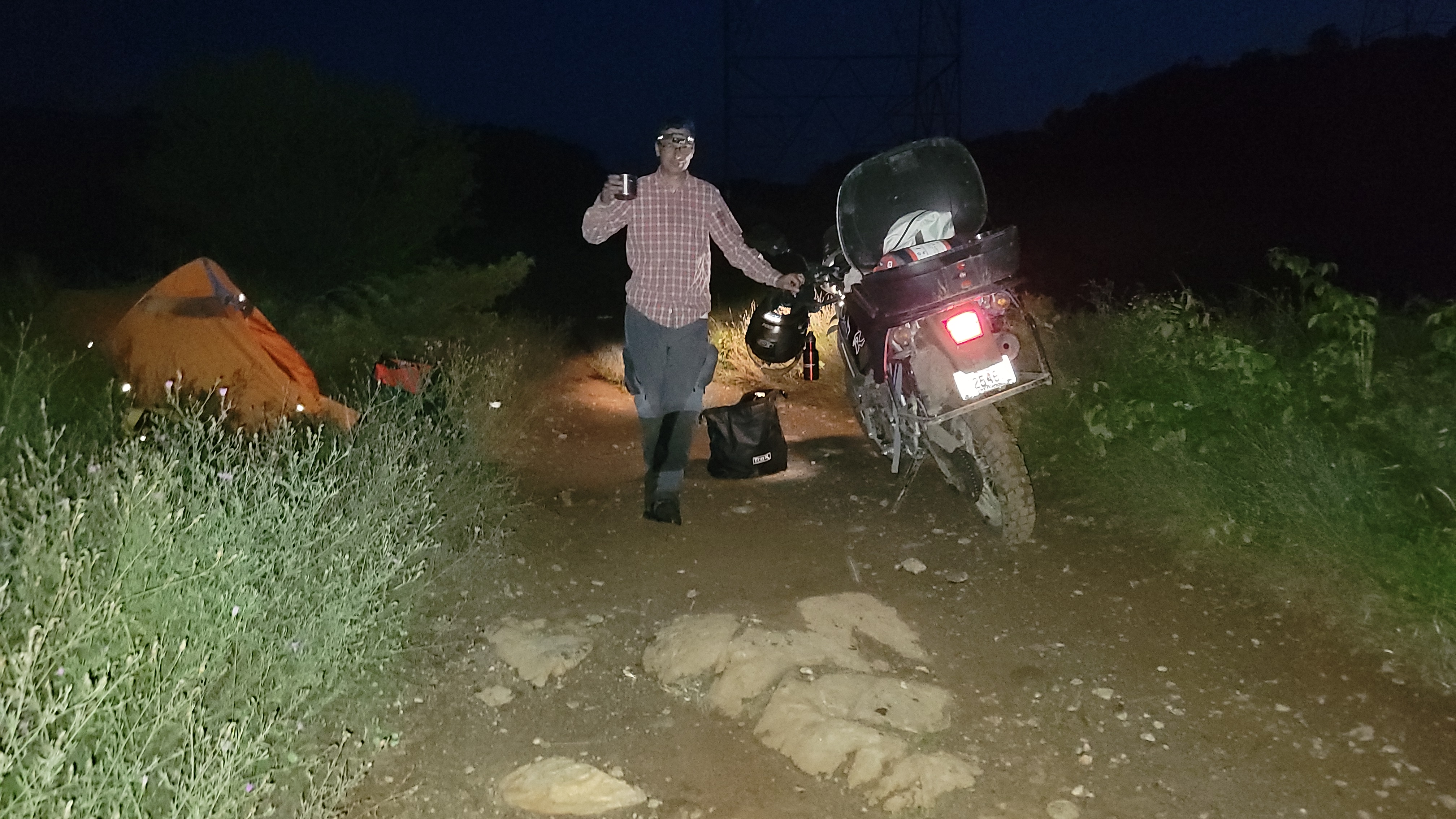 A motorcyclist standing next to his bike at night on a dirt trail in Ontario, Canada.