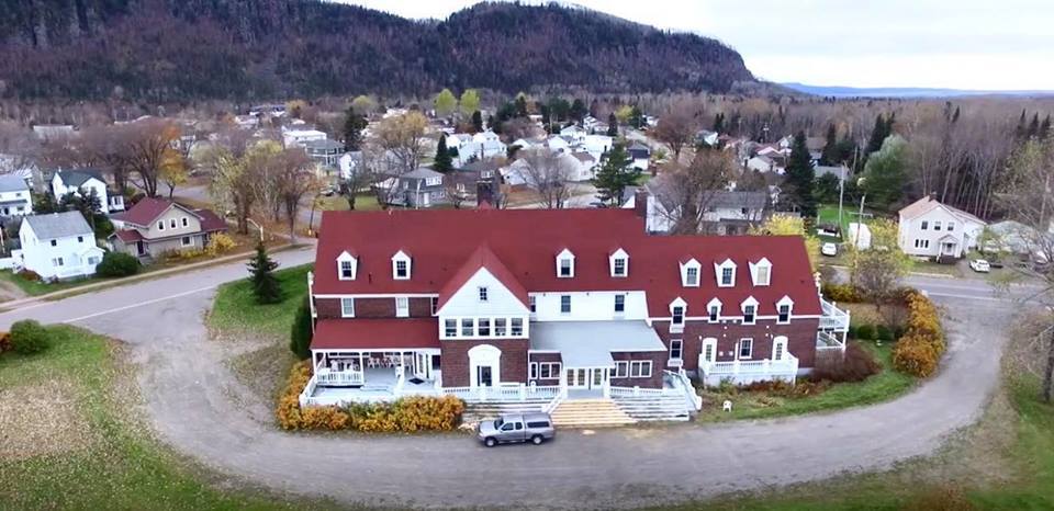 Red Rock Inn; a large, ornate multi-level mansion with red roof, elabroate porch and circular drive, sitting at the edge of town. 