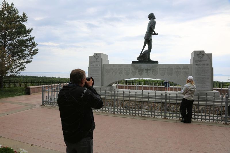 Tourists photograph the statue of Terry Fox running at the Terry Fox Memorial in Thunder Bay on a summer day.