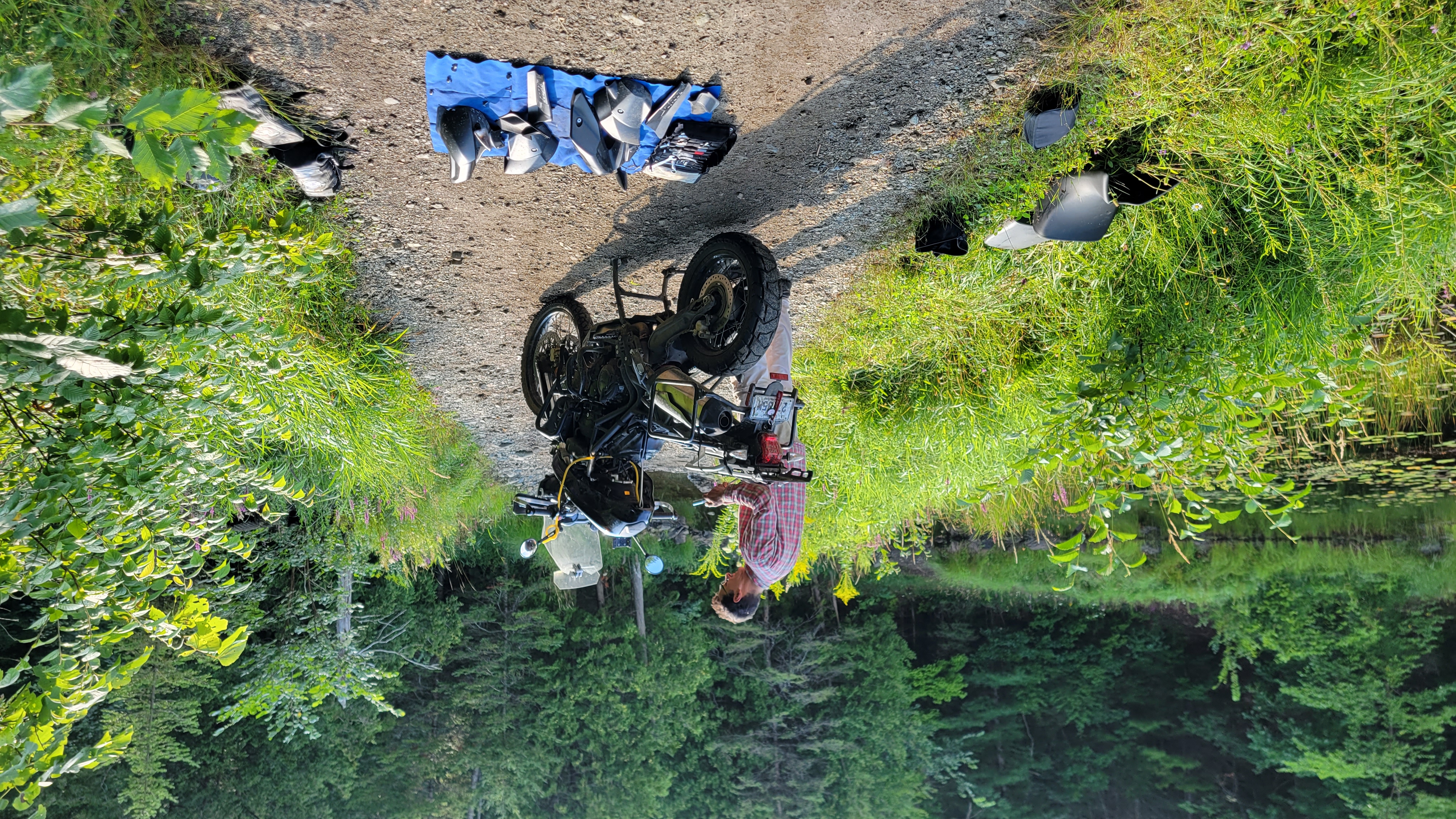 A motorcycle with its parts on the ground being disassembled by a man. 