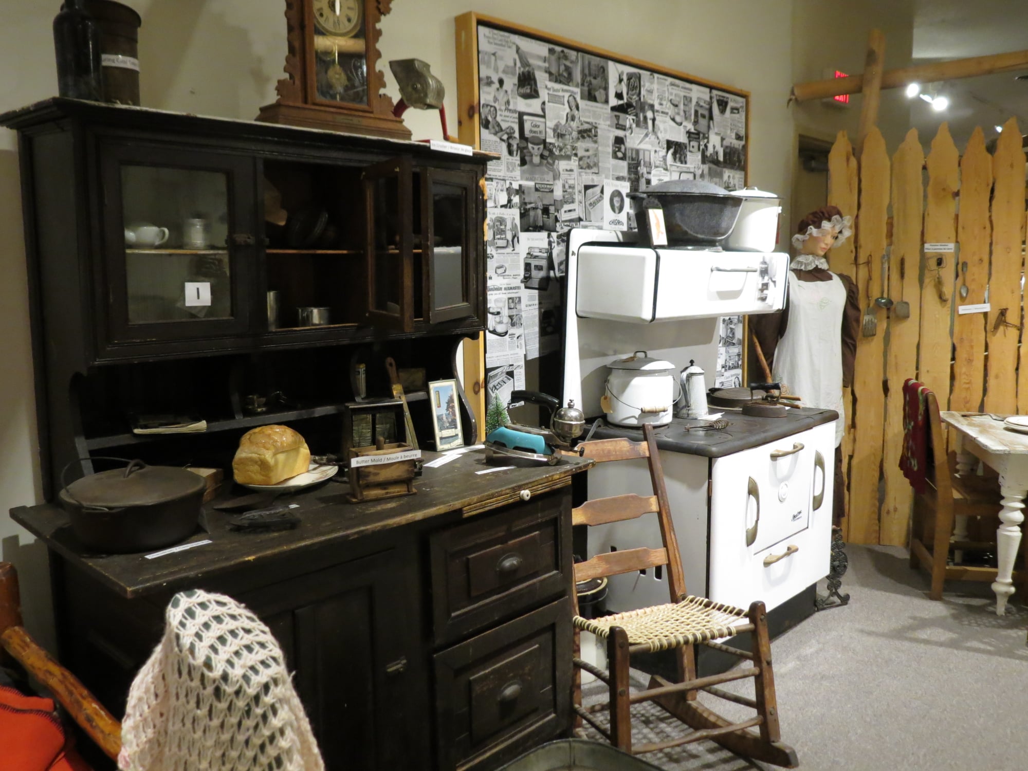 an antique cabinet, stove, and household items on display at the Sturgeon River House museum. 