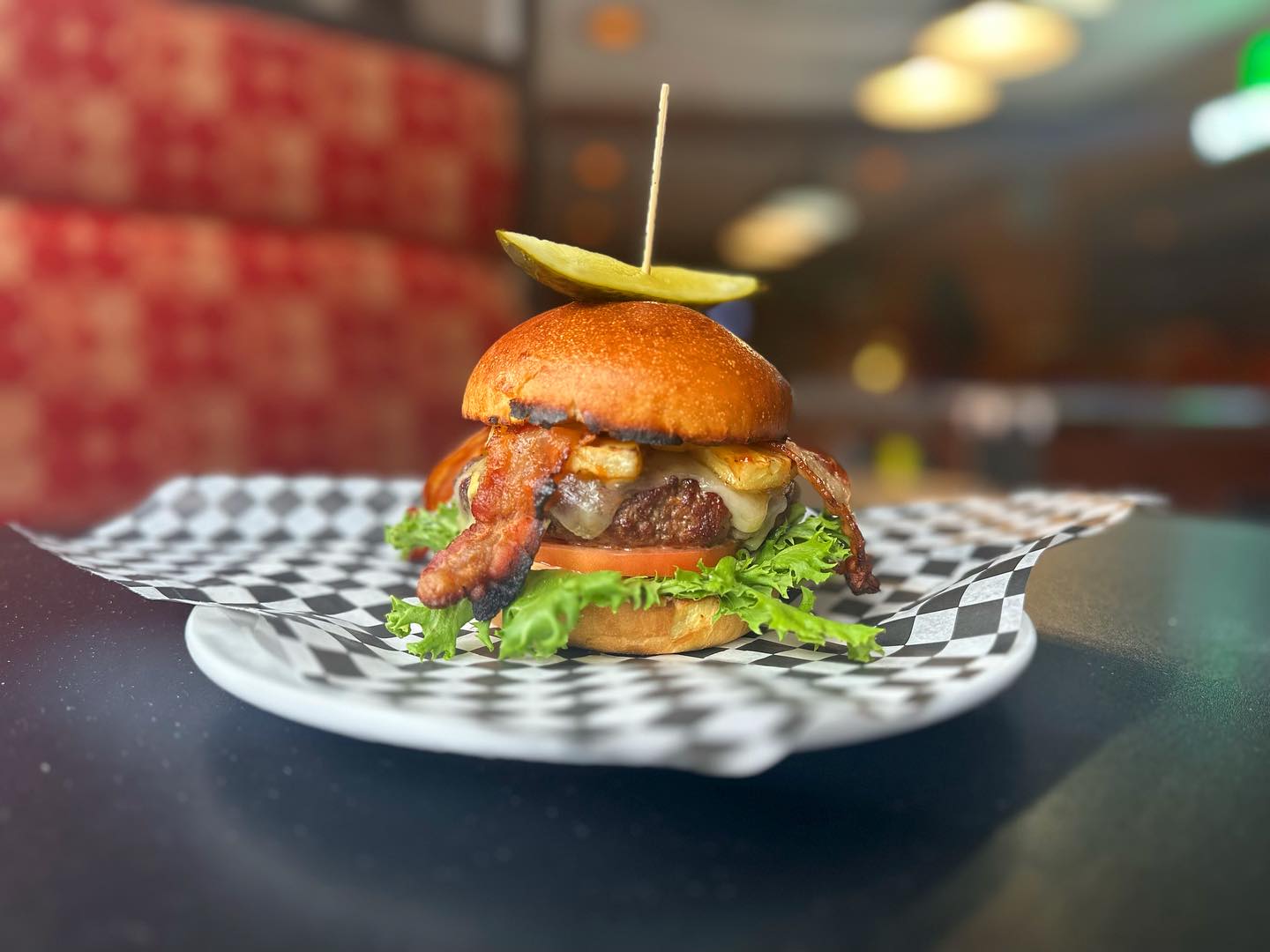 a thick burger with bacon and lettuce on a restaurant table.
