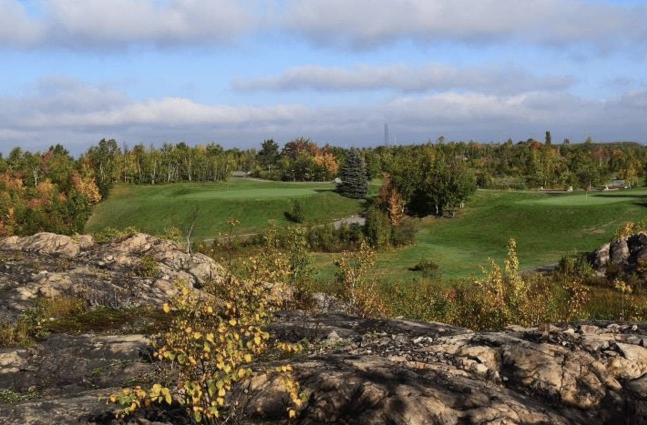 a tidy golf green tucked amid smooth rock ridges and forest.