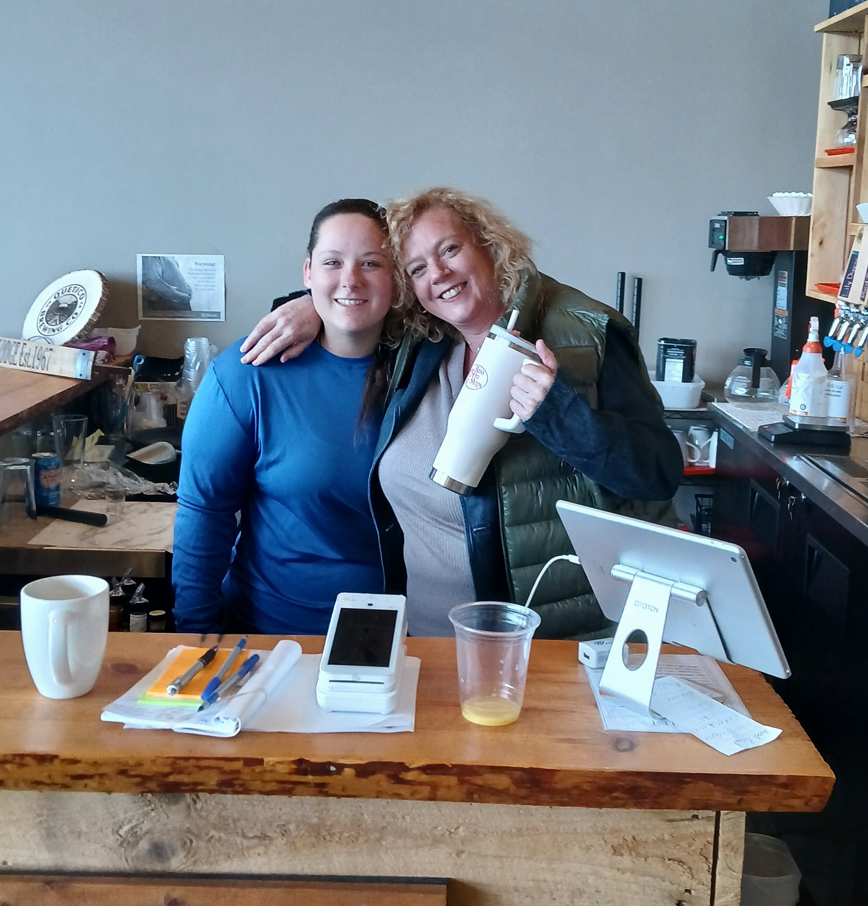 Lisa MacLeod smiles with an employee behind the desk at Branch's Seine River Lodge, her arm around the employee's shoulder.