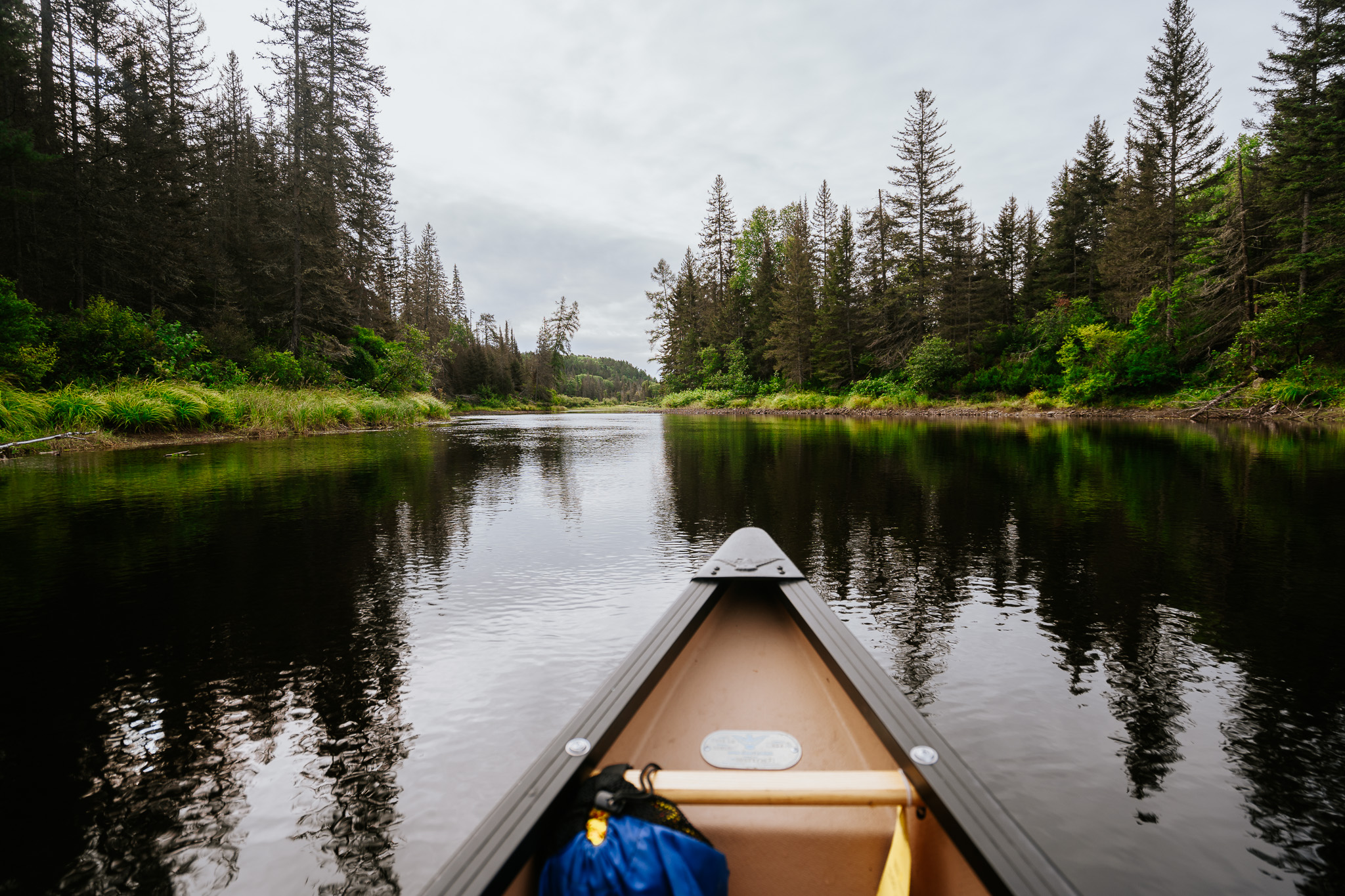 a canoe on shining water surrounded by green forest on the Spanish River.