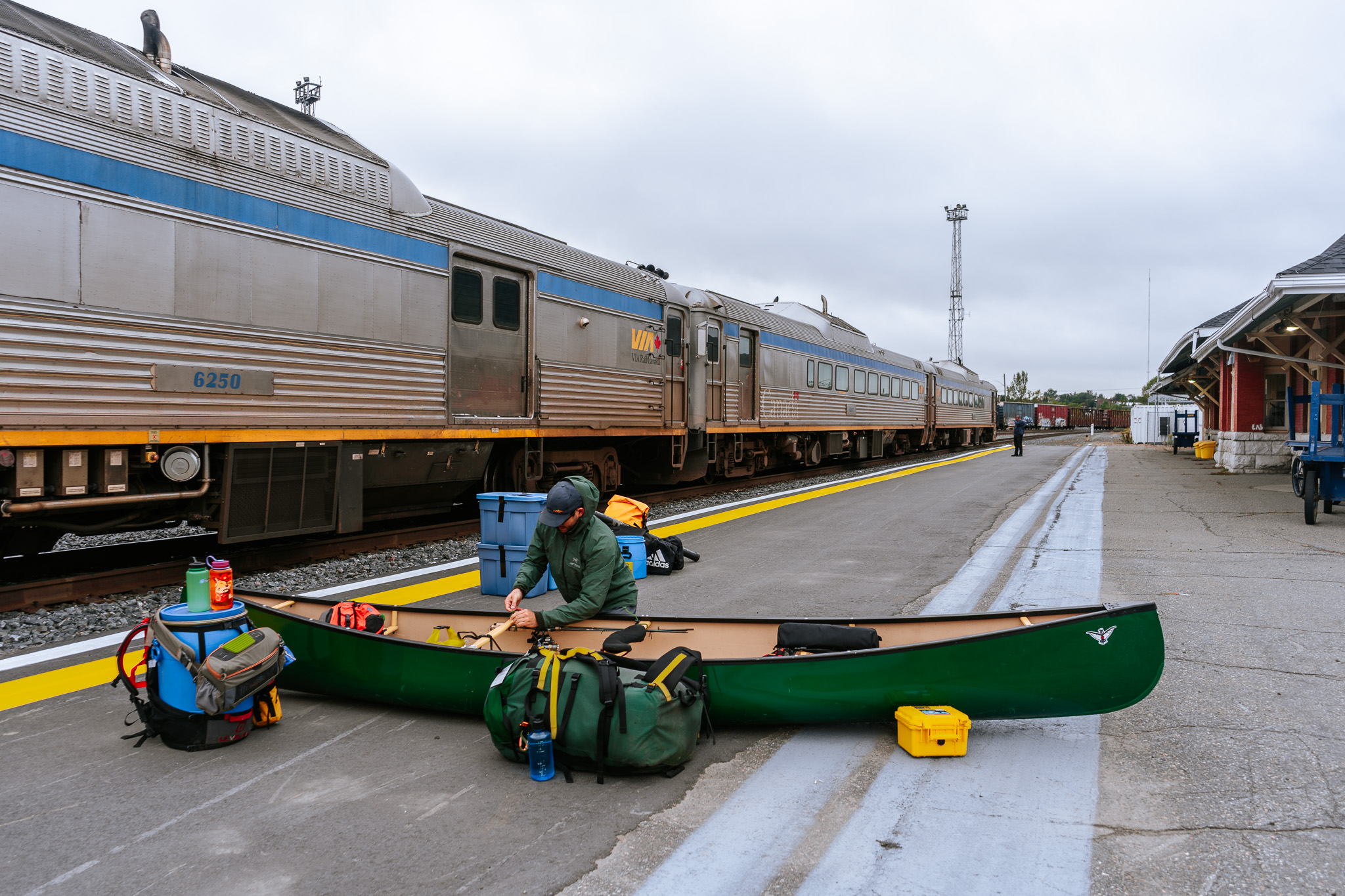 a woman loads her backpacks next to a canoe on a train station platform in Sudbury.