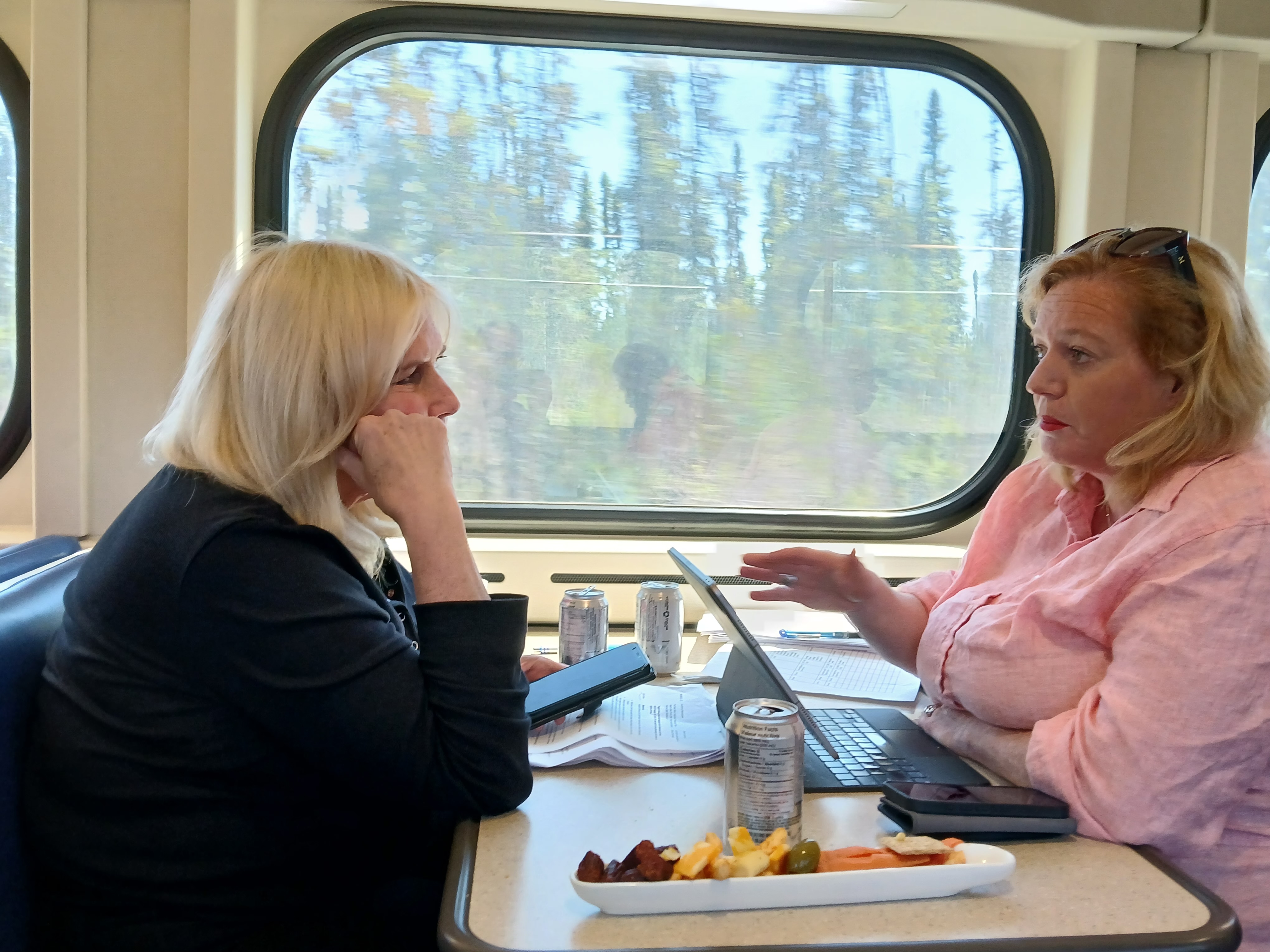 Lisa MacLeod and Susan Truppe talk over their laptops and lunch while sitting at a table aboard the Ontario Northland Polar Express to Moosenee.