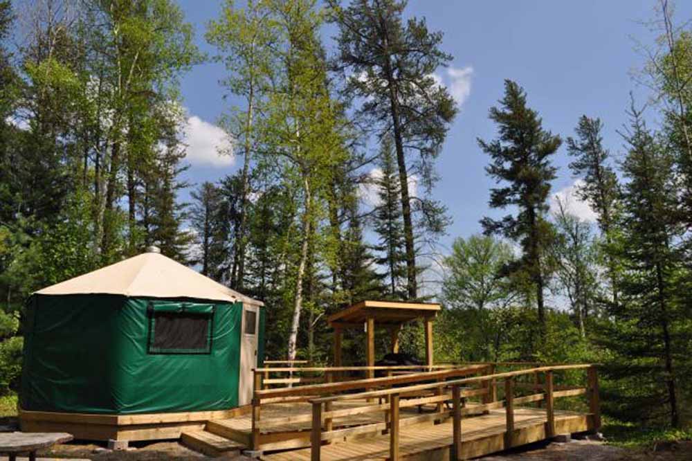 a green yurt with wooden ramp in a forested campsite at Windy Lake Provincial Park.
