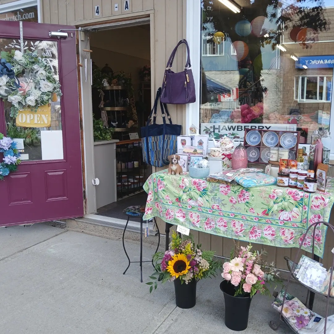 fresh flowers, preserves, handbags and other gifts elegantly displayed outside the purple-doored shop called The Flower Hutch.