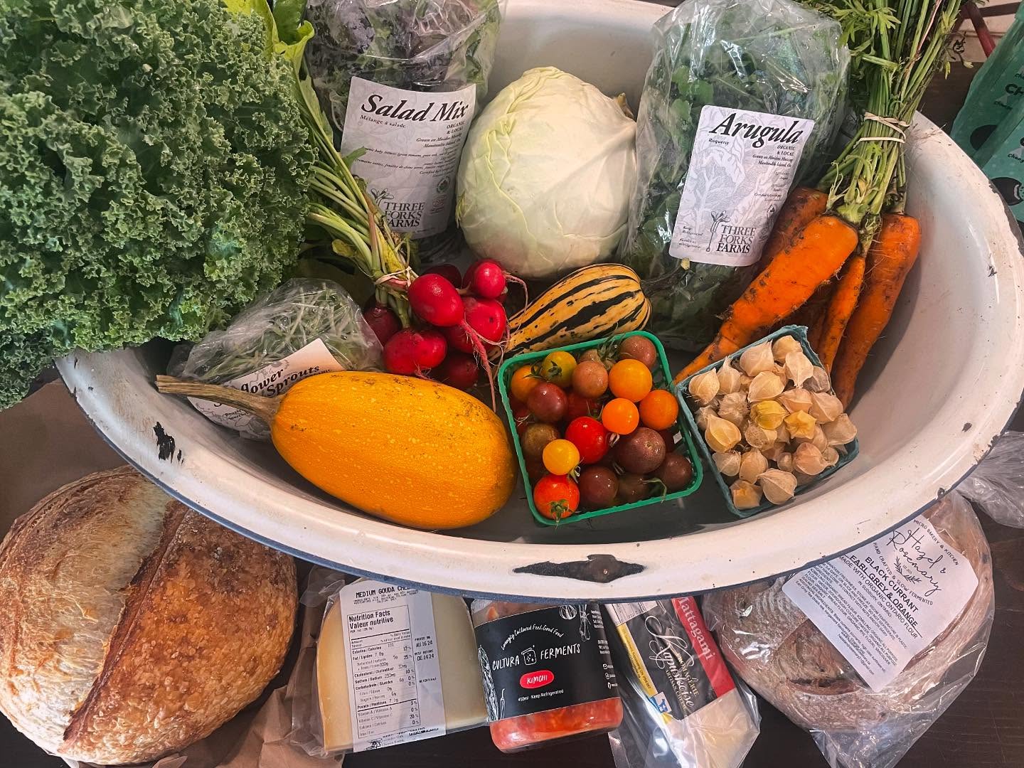 A colourful arrangement of tomatoes, carrots, squash, arugula, bread, cheese and more from Three Forks Farms.