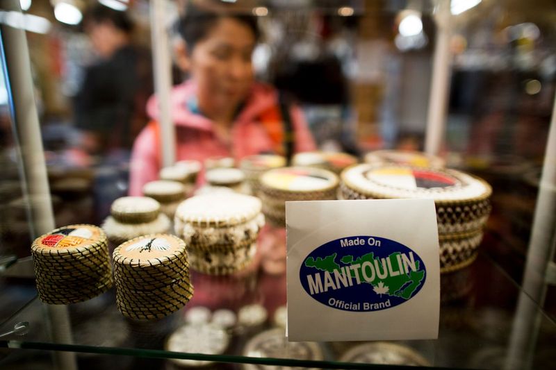 A woman peruses a row of handcrafted quill boxes in a glass case with a label in front of them that reads "Made in Manitoulin".