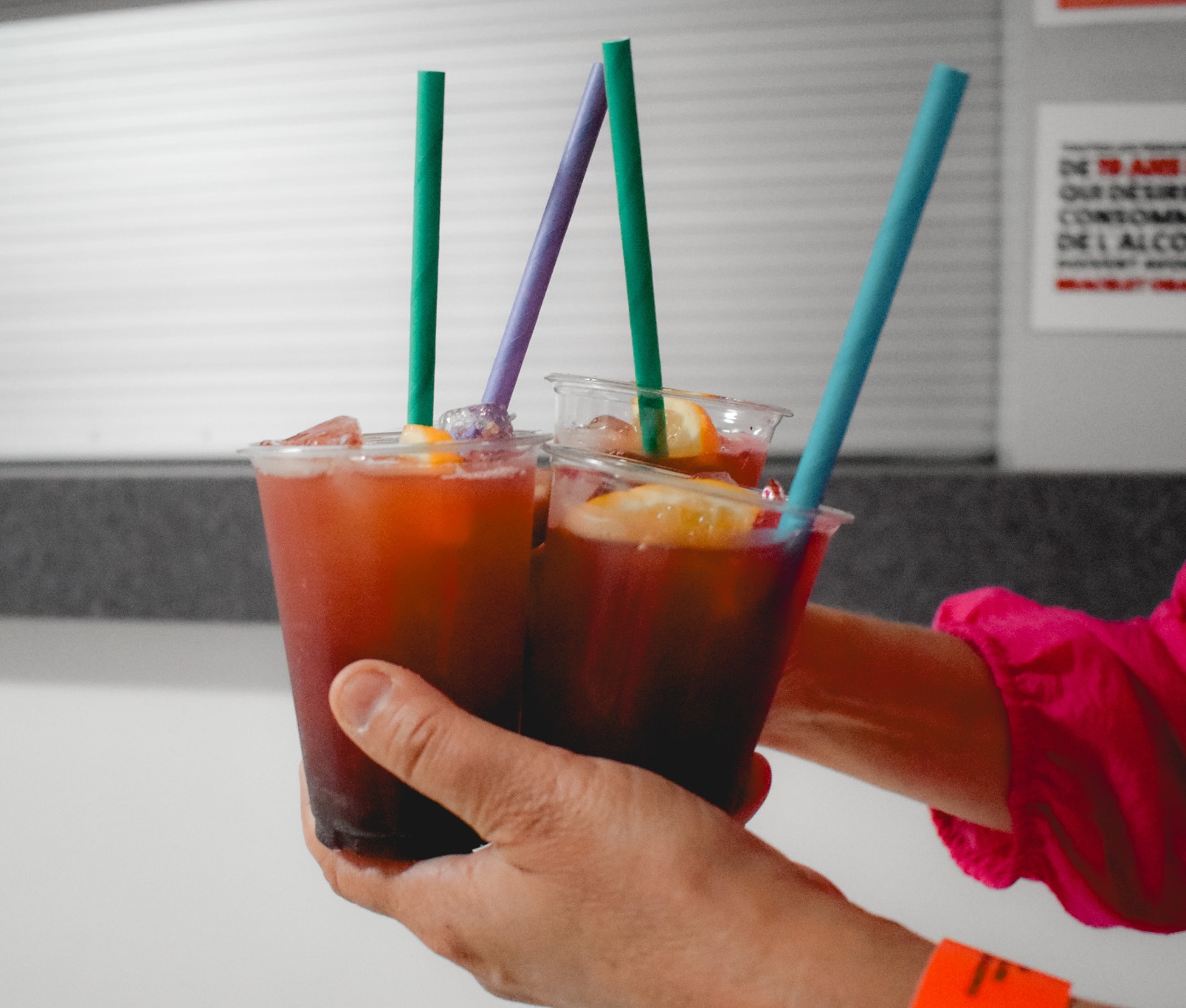 a person carries four ceasars with multicoloured straws and lemon wedges made with Rheault Distillery spirits at a Festibière event.
