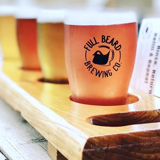 a flyte of different beer flavours and colours in glasses with the Full Beard Brewing label