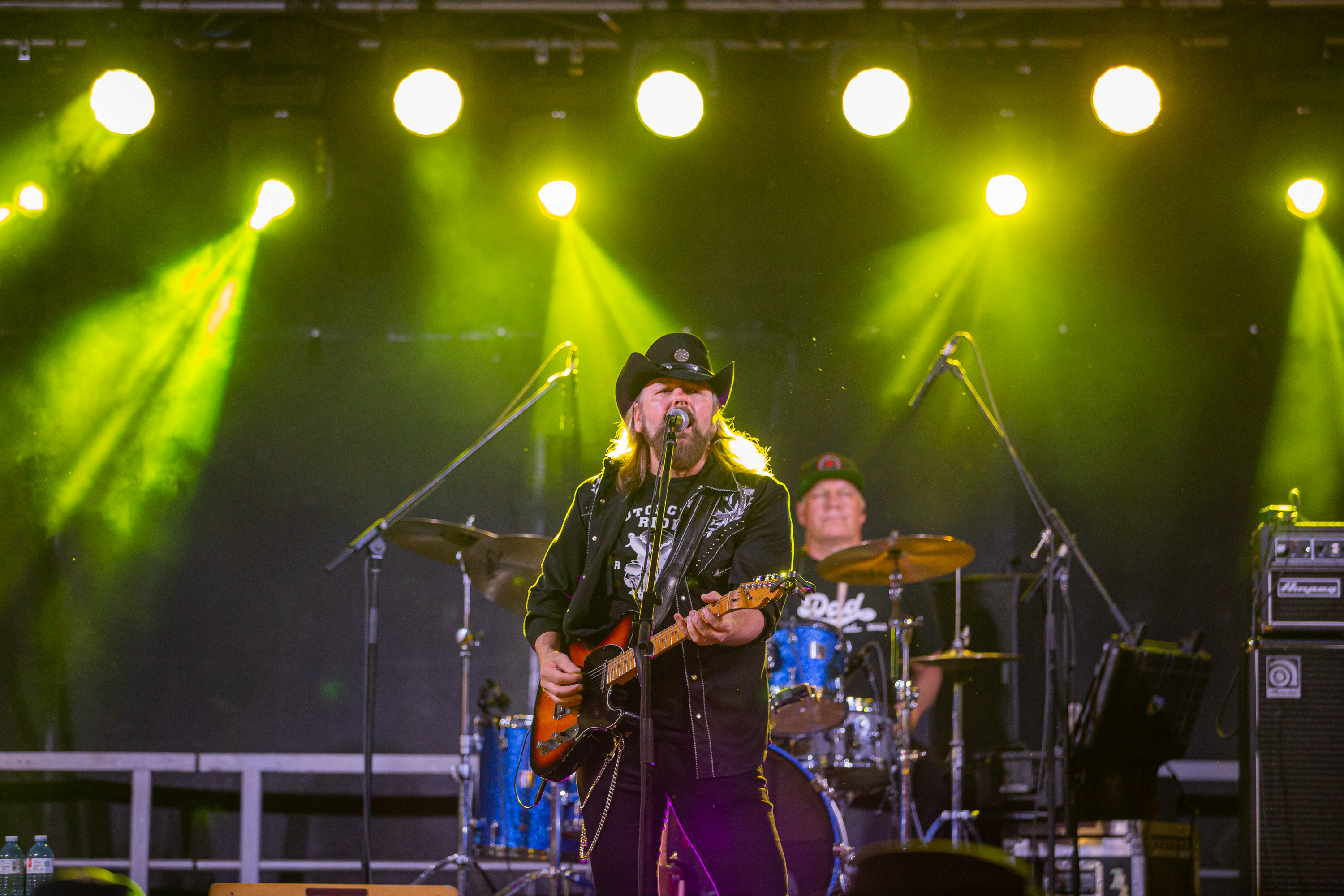 Country music artist Jason McCoy performs with his band under bright green spotlights at Rockin' the Trails 2025 in Tweed.