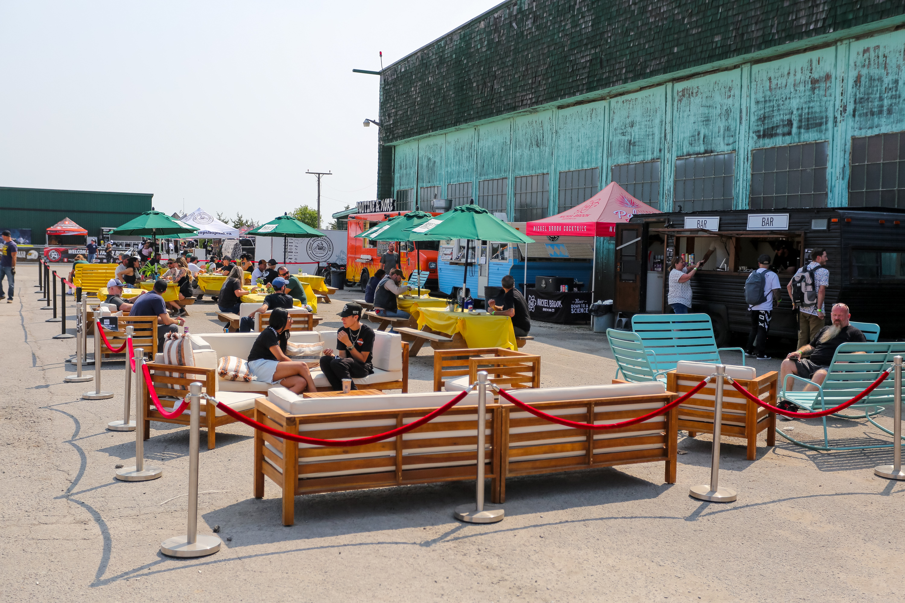 Eventgoers dine at The Commisary at Moto Craft; an expansive outdoor patio with comforable seating and shade umbrellas. 