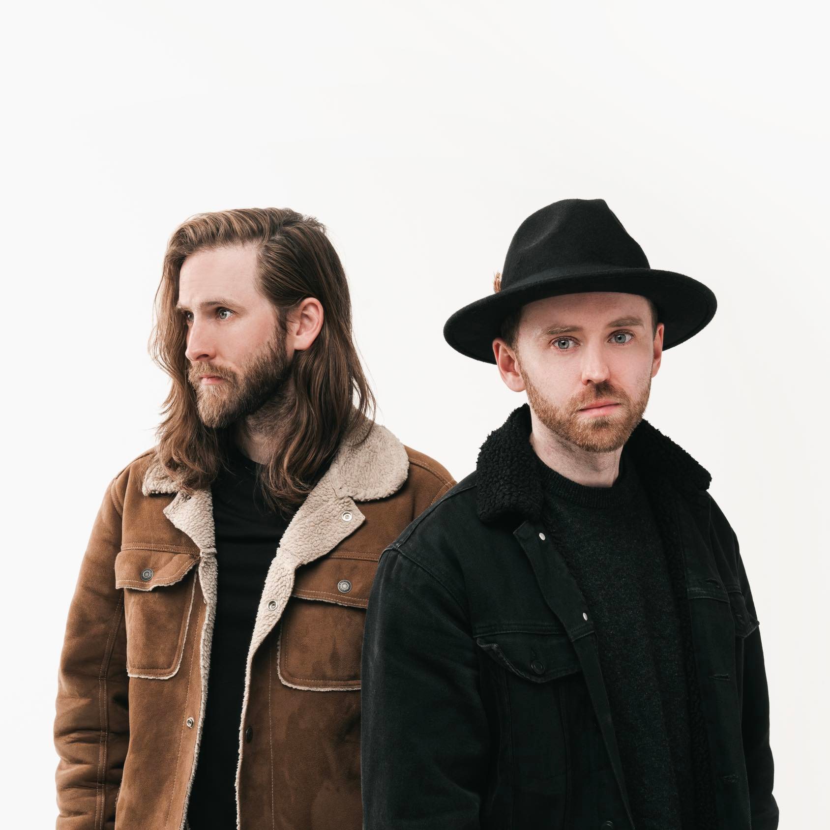 Two men in fall jackets looking pensively in opposite directions.