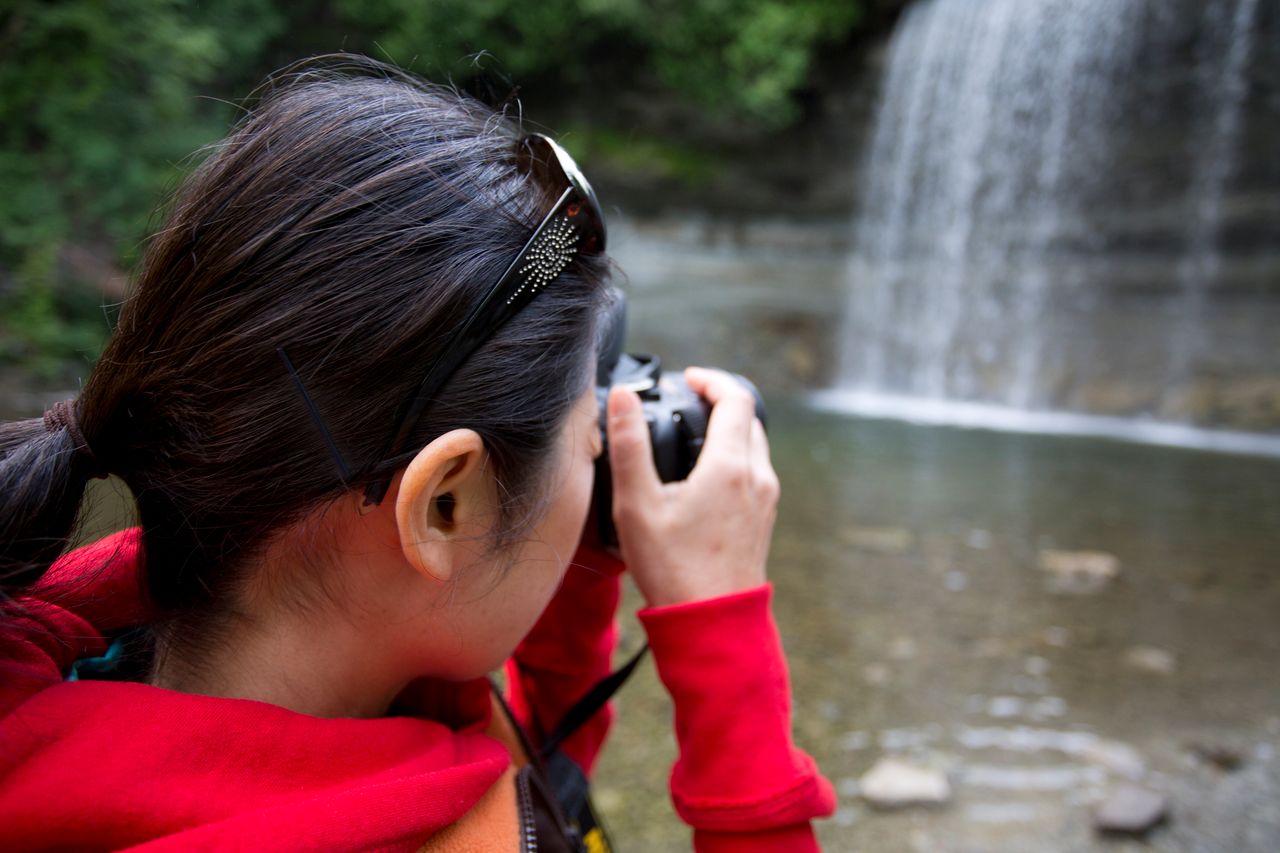 a girl takes a photograph of Bridal Veil Falls