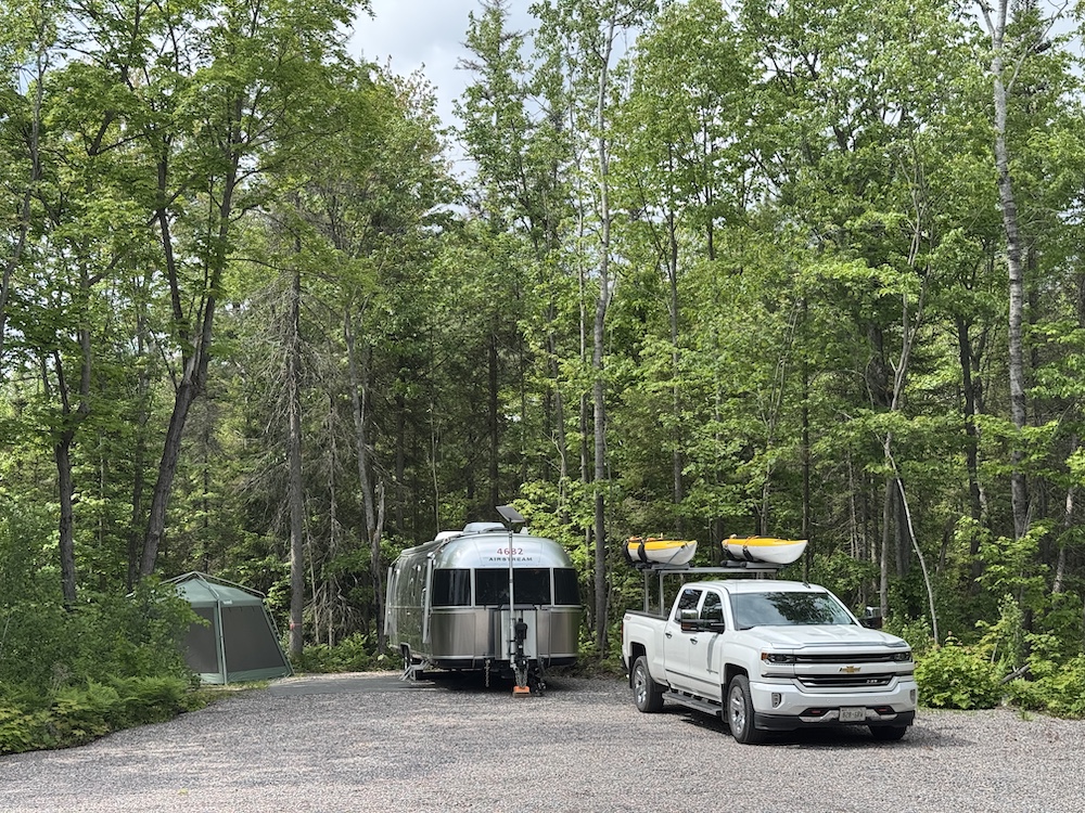 Truck and airstream trailer at a treed campsite