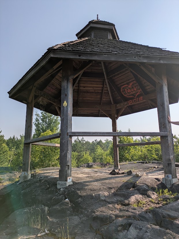 a rough wood gazebo in a forested area