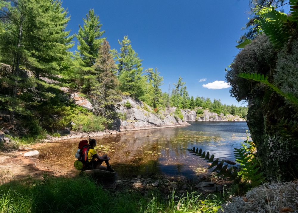 Backpacker sits next to water