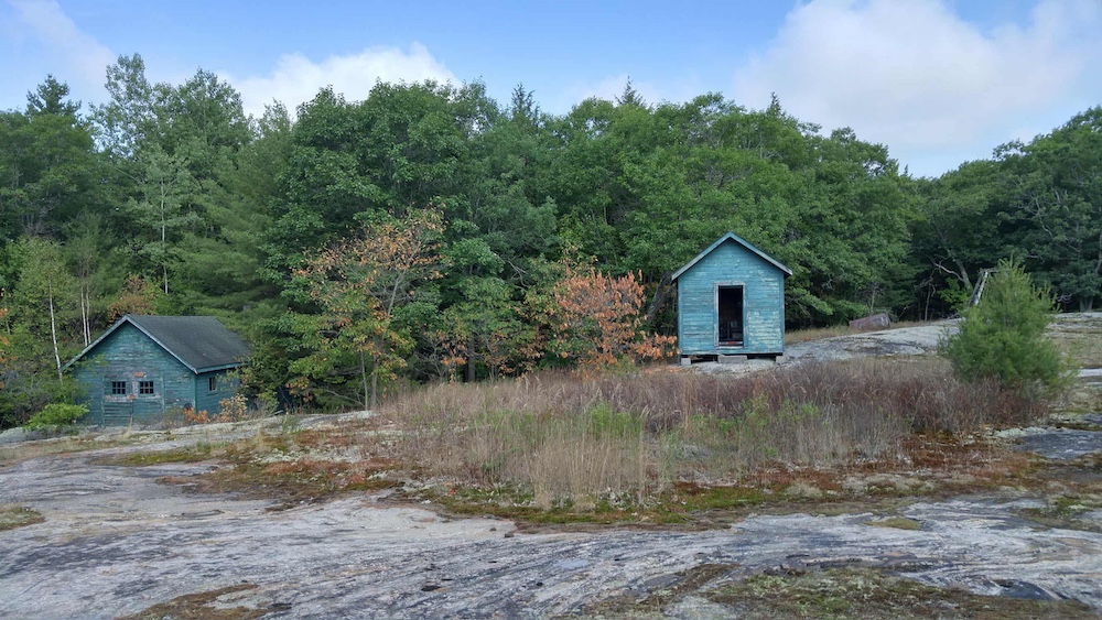 Old green outbuildings on rocky outcrop