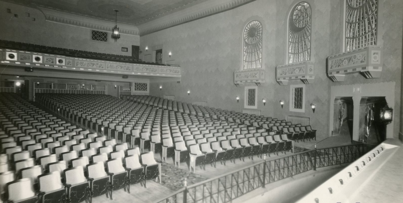 a historic black and white photo of the rows of theatre seats in the Capitol Theatre, with the projection booth light twinkling overhead.