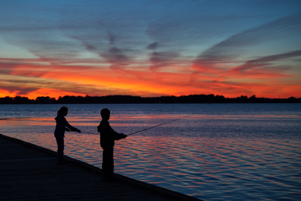 Two kids fishing at sunset