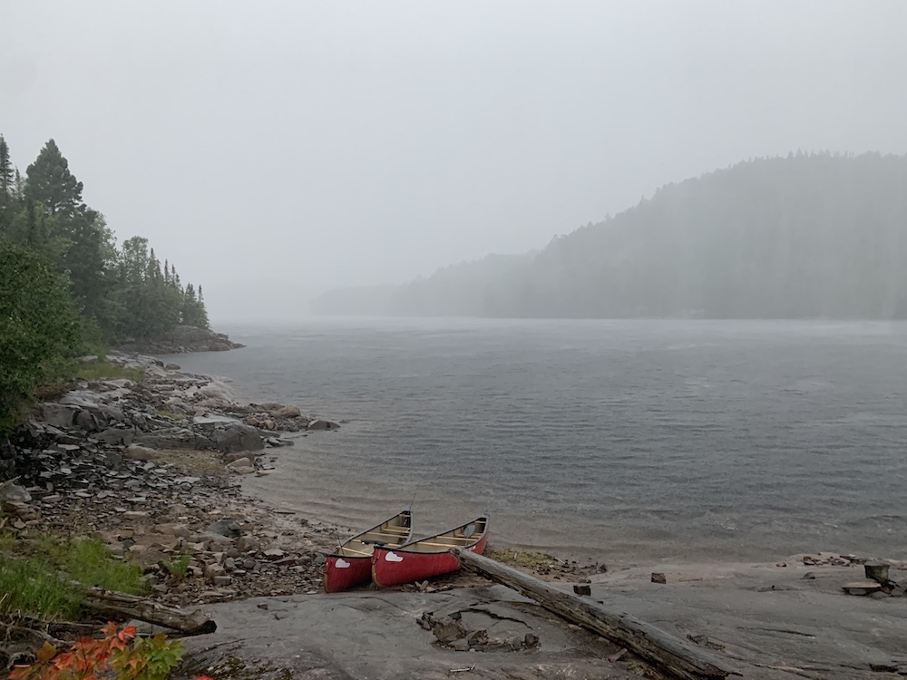 Two red canoes on shore with misty lake and hill in background