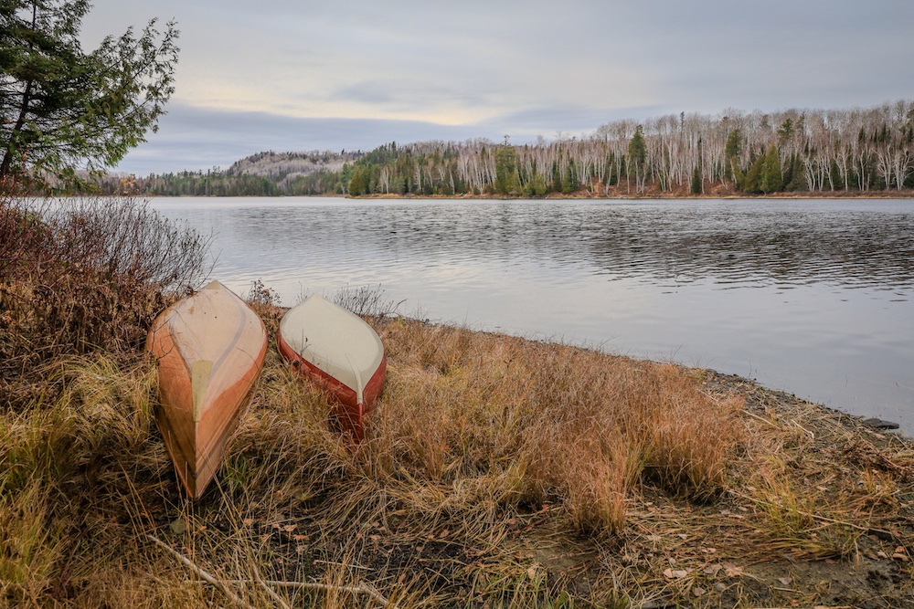 Two canoes turned over on bank of river