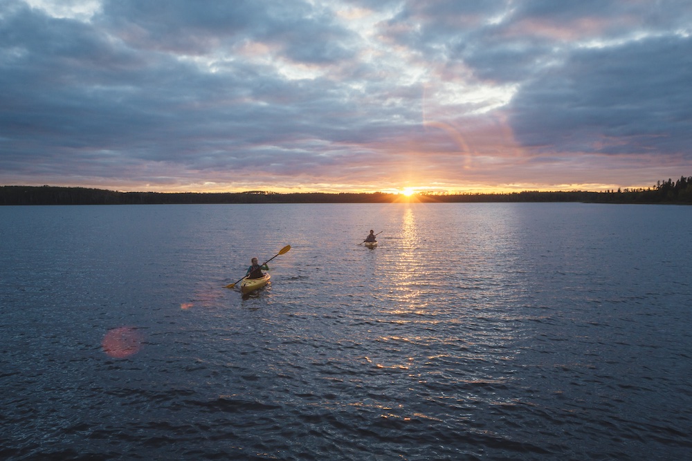 Two kayakers paddling as the sun goes down