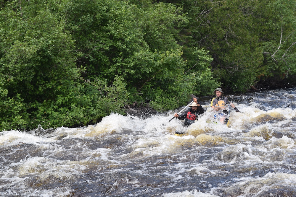 Two paddlers in a canoe running rapids.