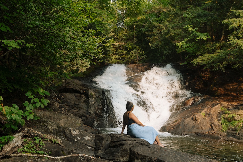 Woman sitting at the bottom of a waterfall