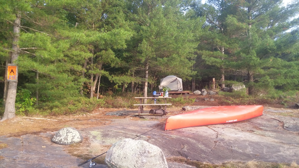 Campsite with red canoe, tent and picnic table