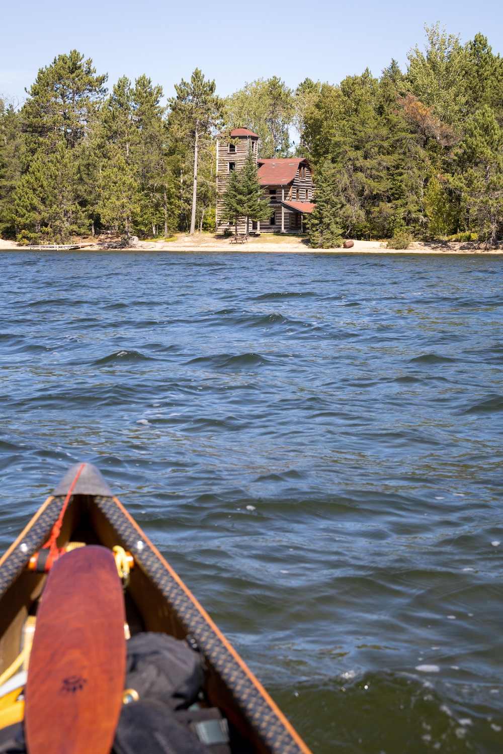 Two story cabin on shore with bow of canoe in foreground