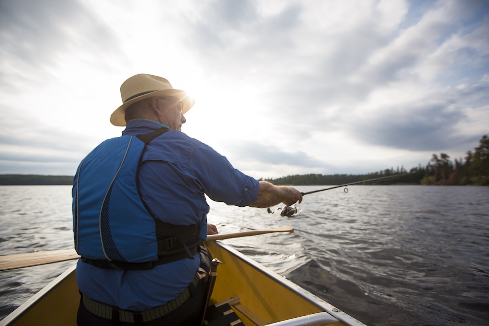Man fishing from bow of canoe