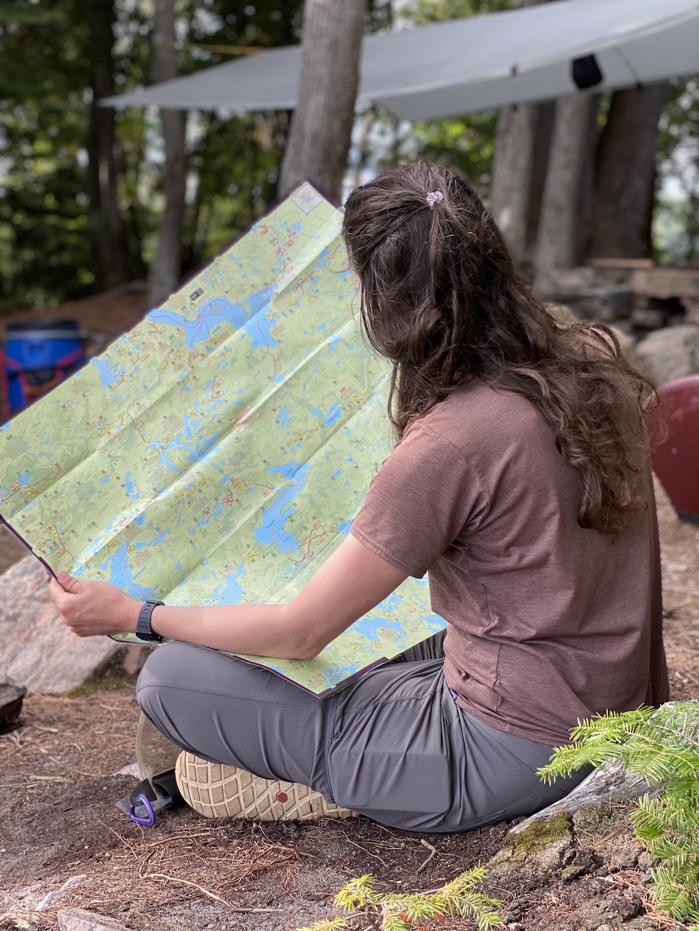 Woman sitting on ground at campsite looking at a map