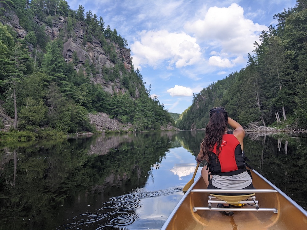 Woman in bow seat paddling through a canyon