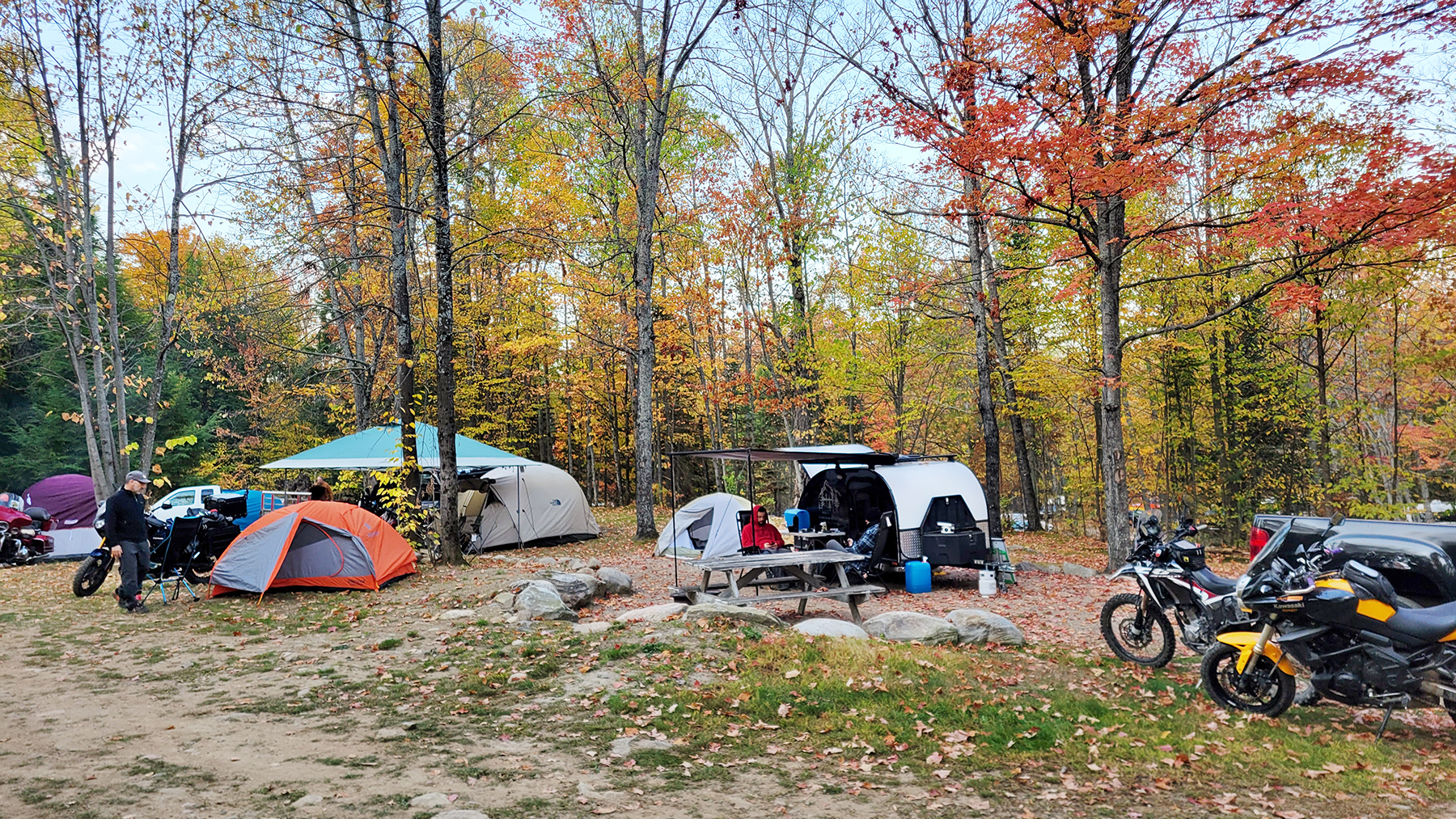 several tents set up among brightly coloured autumn trees with motorcycles parked next to them at Sunny Hill Resort, Ontario. 
