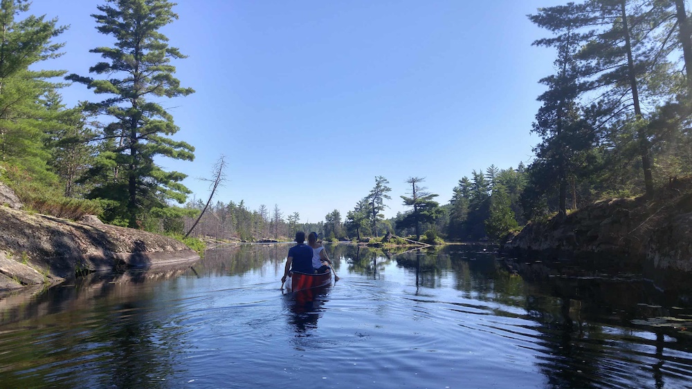 Two people in canoe paddling through narrows