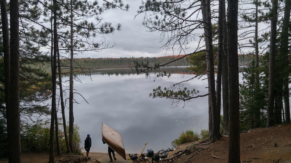 Person portaging canoe down staircase to the lake