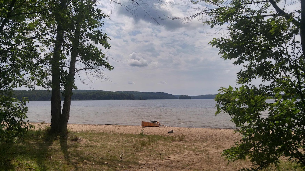 Canoe sits on a beach beside the water