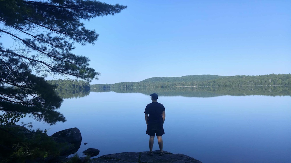 Man stands on rocky shore at edge of lake