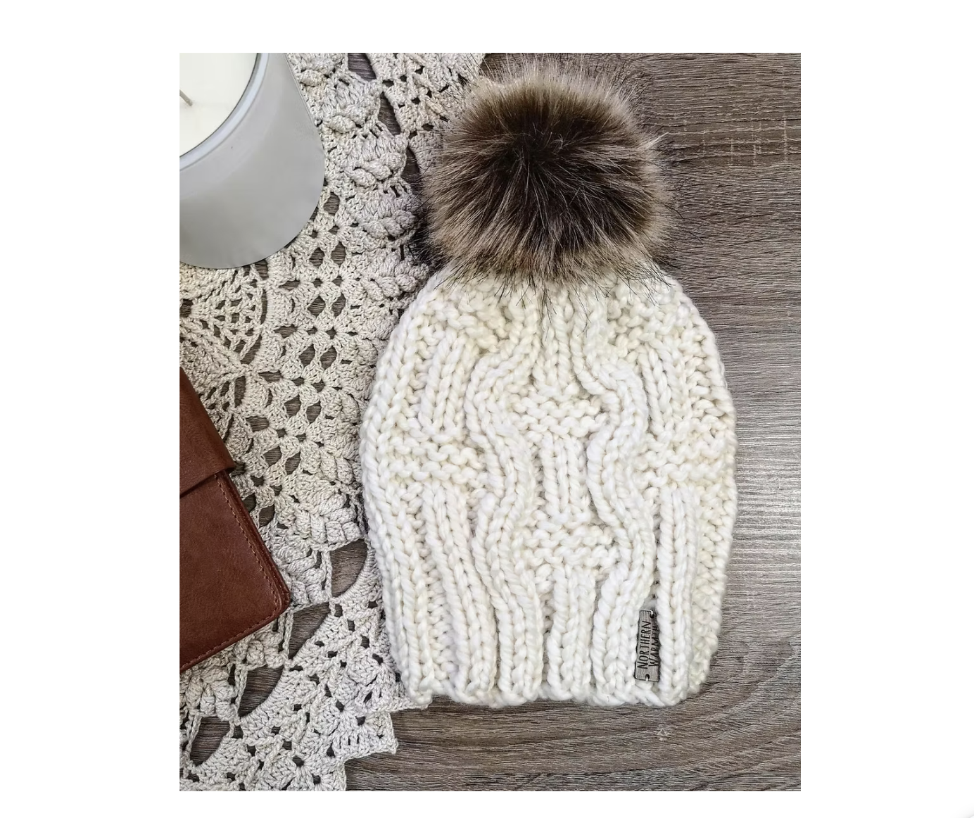 A cream coloured cable-knit toque with a fur pom pom, made in Sault Ste. Marie.
