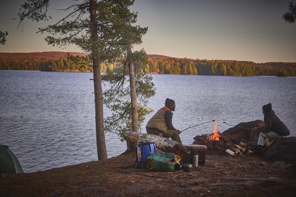 Two people on a campsite sitting by the fire