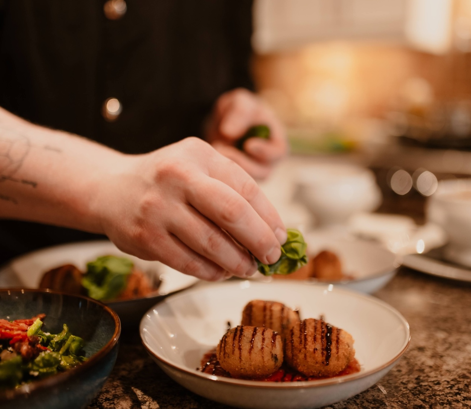 a chef places an herb garnish on several dishes.