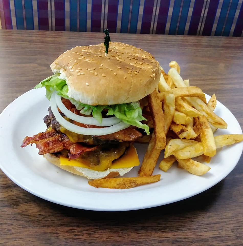 a tall burger stacked with fresh lettuce, onion and tomato and a side of fries from Bay Truck Stop in North Bay.